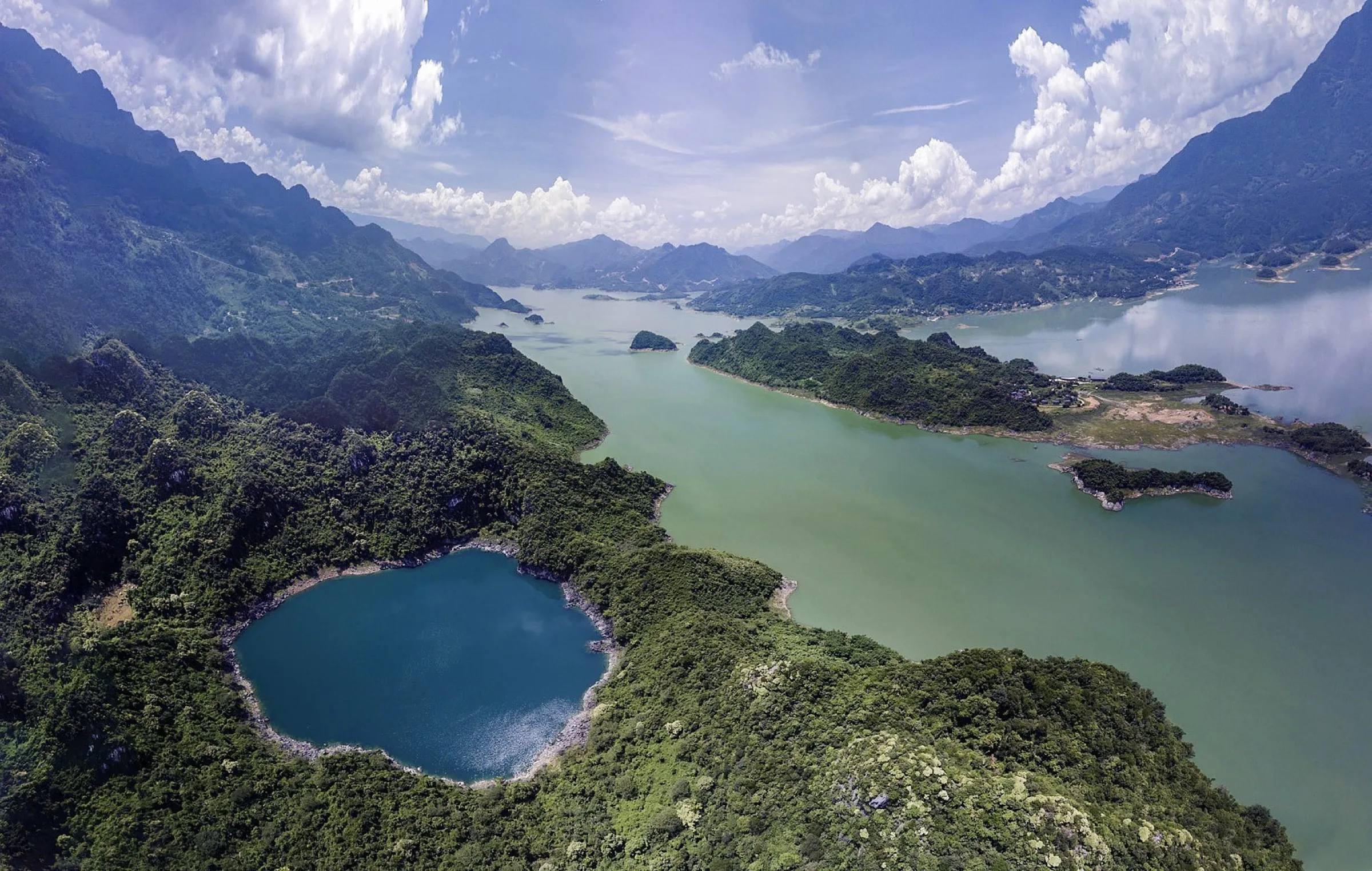Aerial view of the jade Dragon Eye Lake among the forested limestone hills of Hoa Binh, Vietnam.