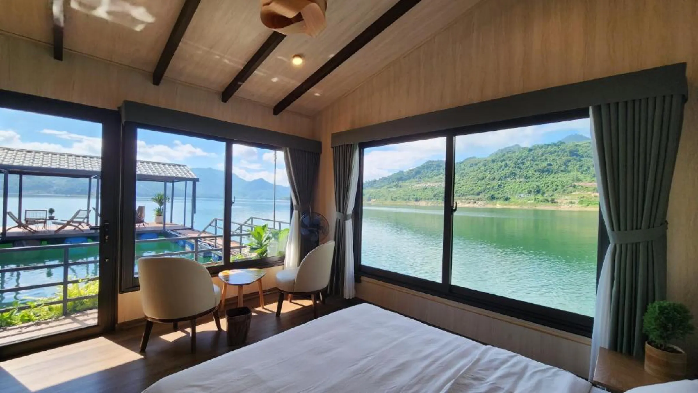A floating-house bedroom with floor-to-ceiling windows opening onto the lake.
