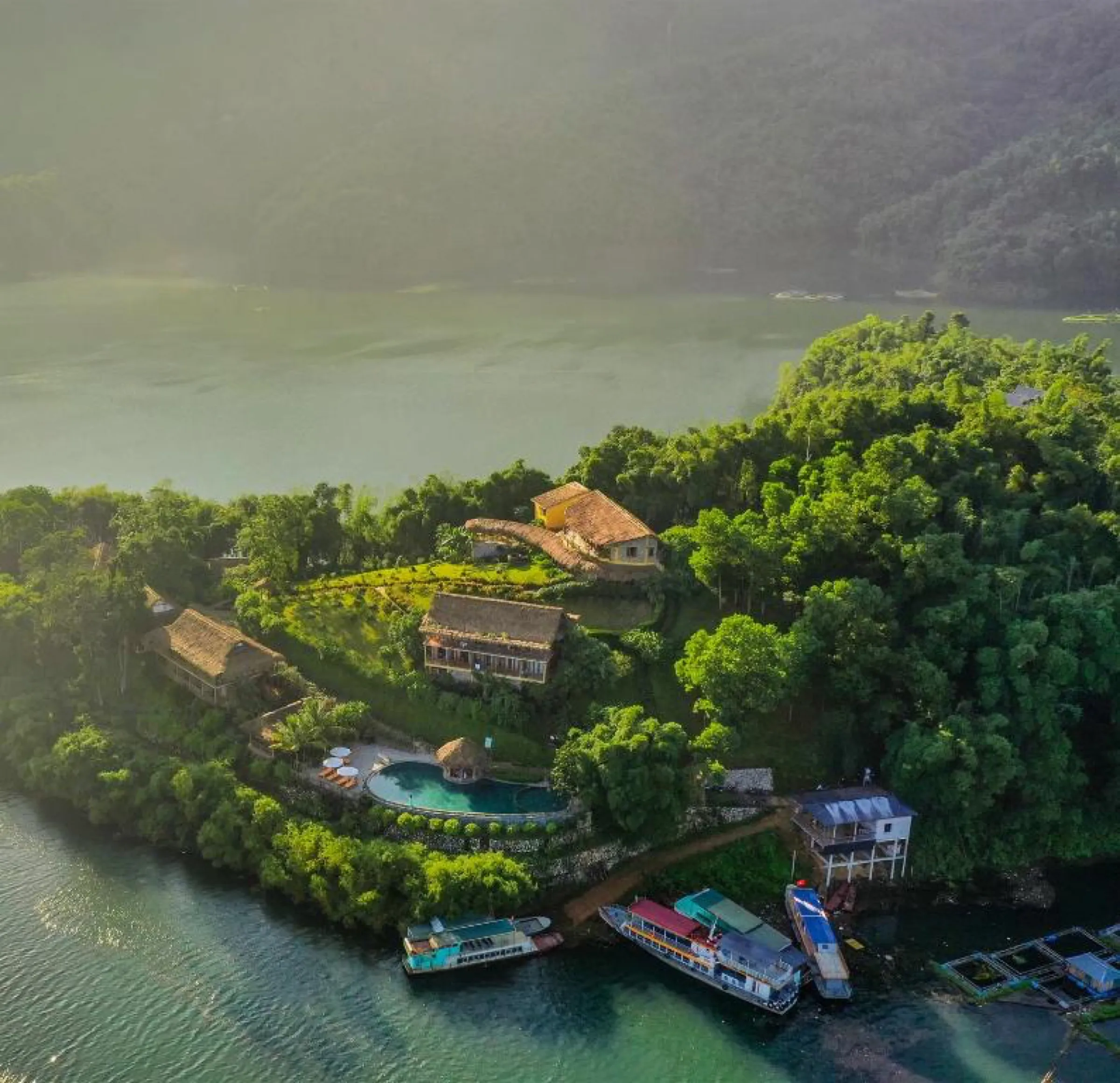 Aerial view of the Mai Chau Hideaway resort and its pool on the forested lakeshore.